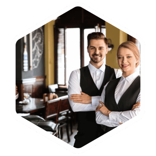 Zwei Restaurantmitarbeitende stehen lächelnd mit verschränkten Armen im Gastraum.