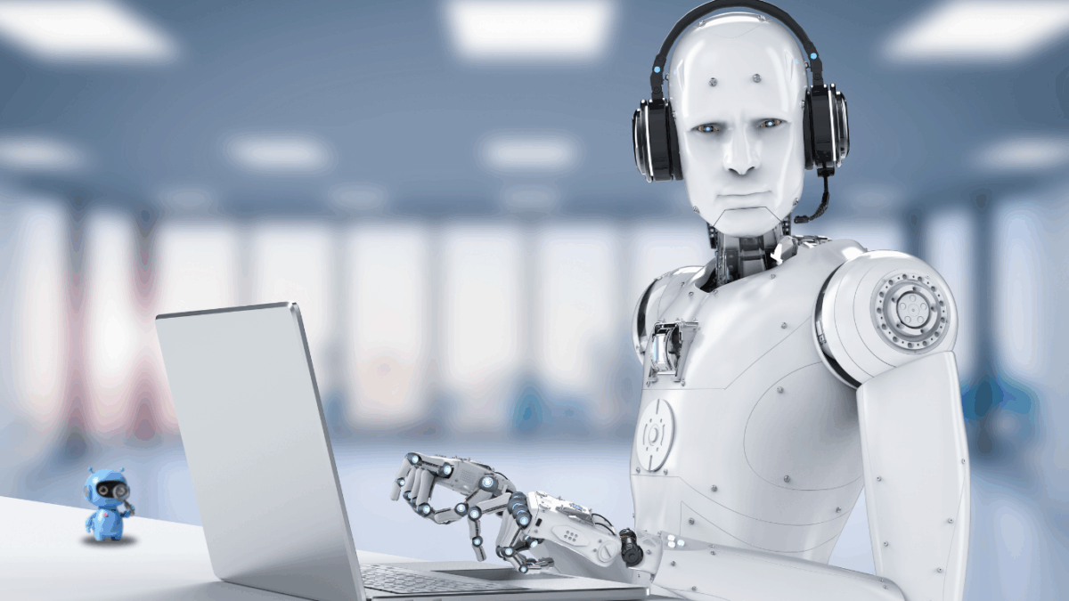 Humanoider Roboter mit Headset sitzt vor einem Laptop in einem modernen Büro.